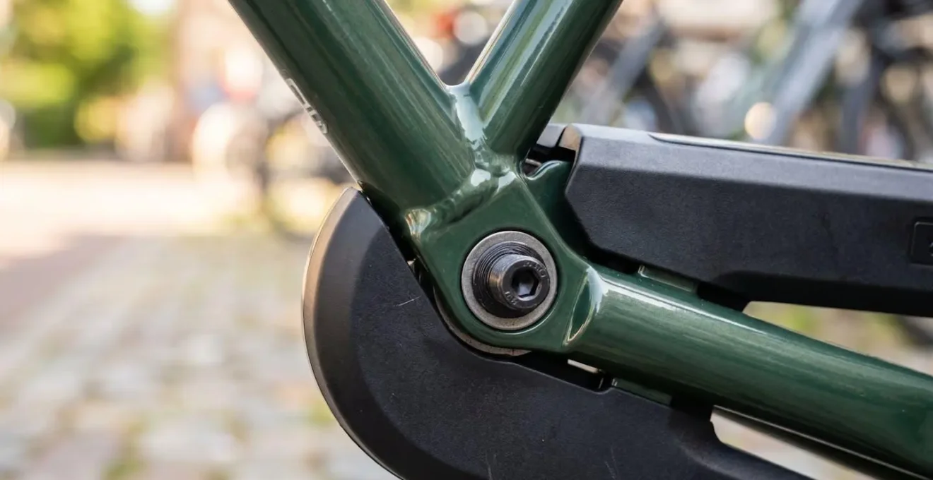 Gros plan détaillé sur la protection de chaîne intégrale d'un vélo hollandais, mettant en valeur la robustesse et la finition soignée du carter métallique